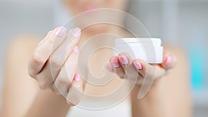 Close-up of female hands holding jag with white skin care cosmetics cream