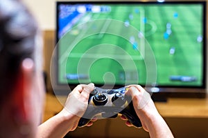Close up of female hands holding a joystick controller while playing a video games at home, narrow depth of field on hands