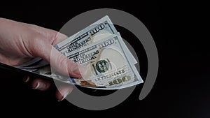 Close-up of female hands holding a pack of one hundred dollar bills.The concept of paying for goods and services, getting paid,