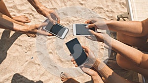 Close-up of female hands holding phones chatting on social network or shopping online on the beach