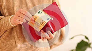 Close up of female hands holding a red leather wallet wih 50 euro banknotes. Payment bills, Monthly expenses, help