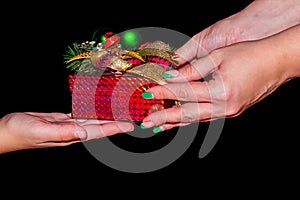 Close-up of female hands are holding a small gift. A woman gives a gift to a child. Close-up hands are giving a Christmas present.