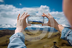 Close-up of female hands holding smartphone and taking photo or video. Woman traveler on a background of beautiful mountain