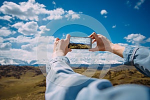 Close-up of female hands holding smartphone and taking photo or video. Woman traveler on a background of beautiful mountain