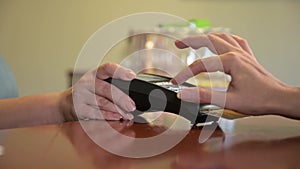 Close-up of female hands holding a terminal in a cafe, restaurant, store. The customer pays for the order by card.  Credit card