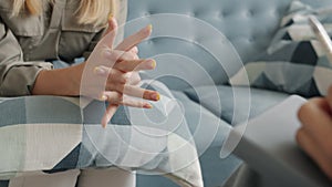 Close-up of female hands holding tissue while nervous woman talking to therapist in office