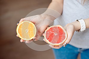 Orange and grapefruit in human`s hands.