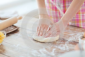 Close up of female hands kneading dough at home