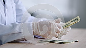 Close-up female hands in latex gloves counting dollars salary profit investment, unrecognizable woman doctor nurse