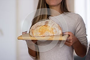 Close-up of female hands with loaf of bread on wooden board photo