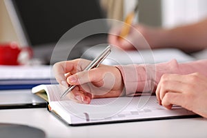 Close up female hands make an entry in diary