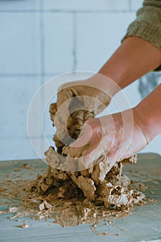 Close-up female hands mixing clay ball before working on a pottery wheel