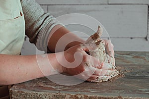 Close-up female hands mixing clay ball before working on a pottery wheel