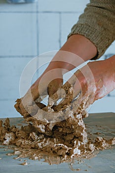 Close-up female hands mixing clay ball before working on a pottery wheel