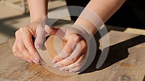 Close-up female hands mixing clay ball before working on a pottery wheel