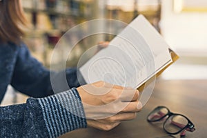 Female hands open book in library