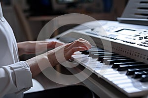 Close-up of female hands playing the synthesizer, shallow depth of field