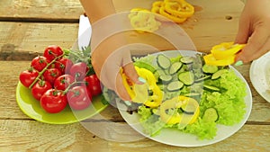 Close-up of female hands put pieces of pepper in a plate with salad. Camera moves to dolly from