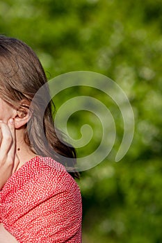 Close-up Of Female Hands Putting Hearing Aid In Ear. Modern digital in the ear hearing aid for deafness and the hard of hearing
