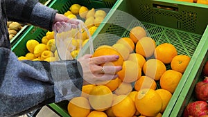 Close up of female hands putting oranges into reusable produce eco bag