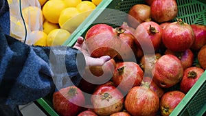 Close up of female hands putting pomegranates into reusable produce eco bag