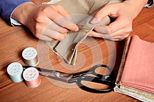 Close-up female hands sewing fabric on old wooden table