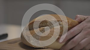 Close up of female hands slicing white bread in slow motion on a wooden board. Action. Cutting freshly baked round