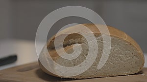 Close up of female hands slicing white bread in slow motion on a wooden board. Action. Cutting freshly baked round