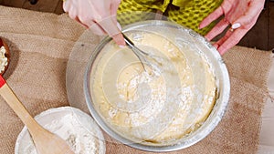 Close-up of female hands stirring the dough with a whisk while preparing delicious cakes in the kitchen.