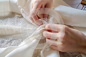 Close up female hands stitch white fabric on modern sewing machine