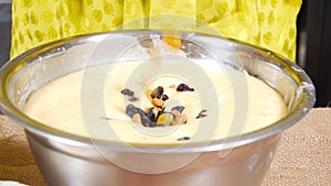 Close-up of female hands throwing a handful of multi-colored raisins into a dish with dough. Cooking Easter cake or