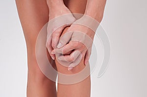 Close-up of female hands touching leg, feeling pain in knee.