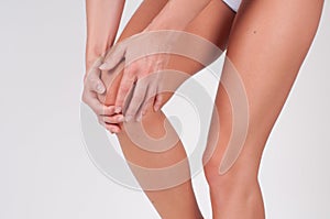 Close-up of female hands touching leg, feeling pain in knee.