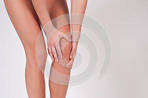 Close-up of female hands touching leg, feeling pain in knee.