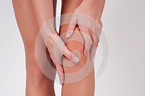 Close-up of female hands touching leg, feeling pain in knee.