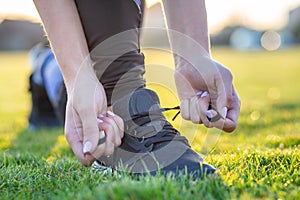 Close-up of female hands tying shoelace on running shoes before practice. Runner getting ready for training. Sport active