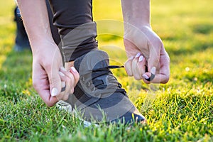 Close-up of female hands tying shoelace on running shoes before practice. Runner getting ready for training. Sport active