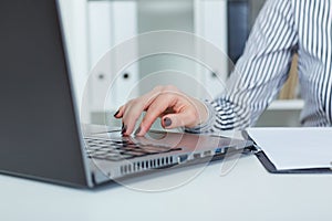 Close up of female hands typing on laptop keyboard, just hands at the table.