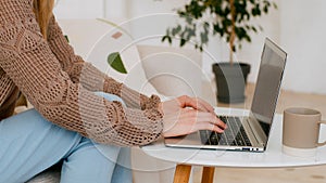 Close up female hands typing laptop at living room. Unrecognizable business woman with computer work at home office sit