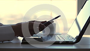 close-up, female hands typing something on a laptop keyboard. At the same time, a business woman responds to messages in