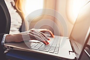 Close-up of female hands using laptop. Woman working while going on business trip by plane