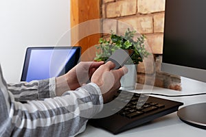 Close-up of female hands using modern smart phone while working at office with computer, businesswoman typing text message on her