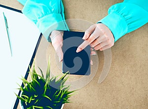 Close-up of female hands using smart phone while working on computer at modern office interior, businesswoman typing