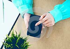 Close-up of female hands using smart phone while working on computer at modern office interior, businesswoman typing