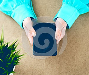 Close-up of female hands using smart phone while working on computer at modern office interior, businesswoman typing text message