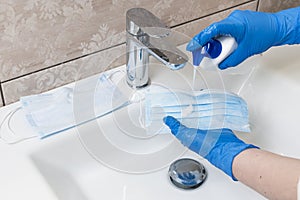 Close-up of female hands washing disposable medical face mask with soap. Deficiency of personal care product during the epidemic