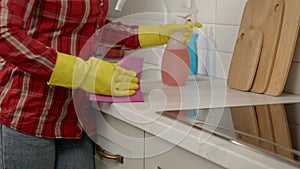 Close-up of female hands washing kitchen countertop from grease using detergent