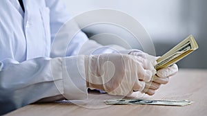 Close-up female hands in white latex gloves pharmacist doctor scientist in medical coat sits at table with bottle of