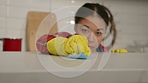 Close-up of female hands wiping kitchen countertop surface with rag at home