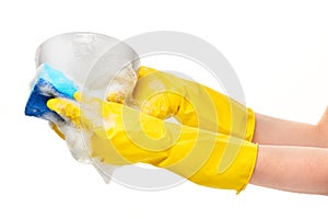 Close up of female hands in yellow protective rubber gloves washing white bowl with blue cleaning sponge